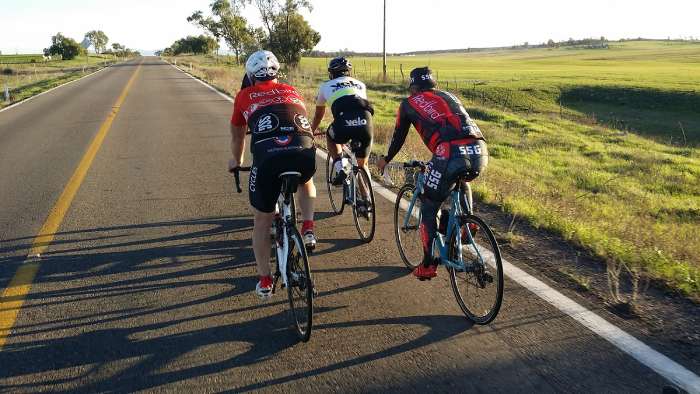 Cyclists riding past green fields outside of Ensenada, California
